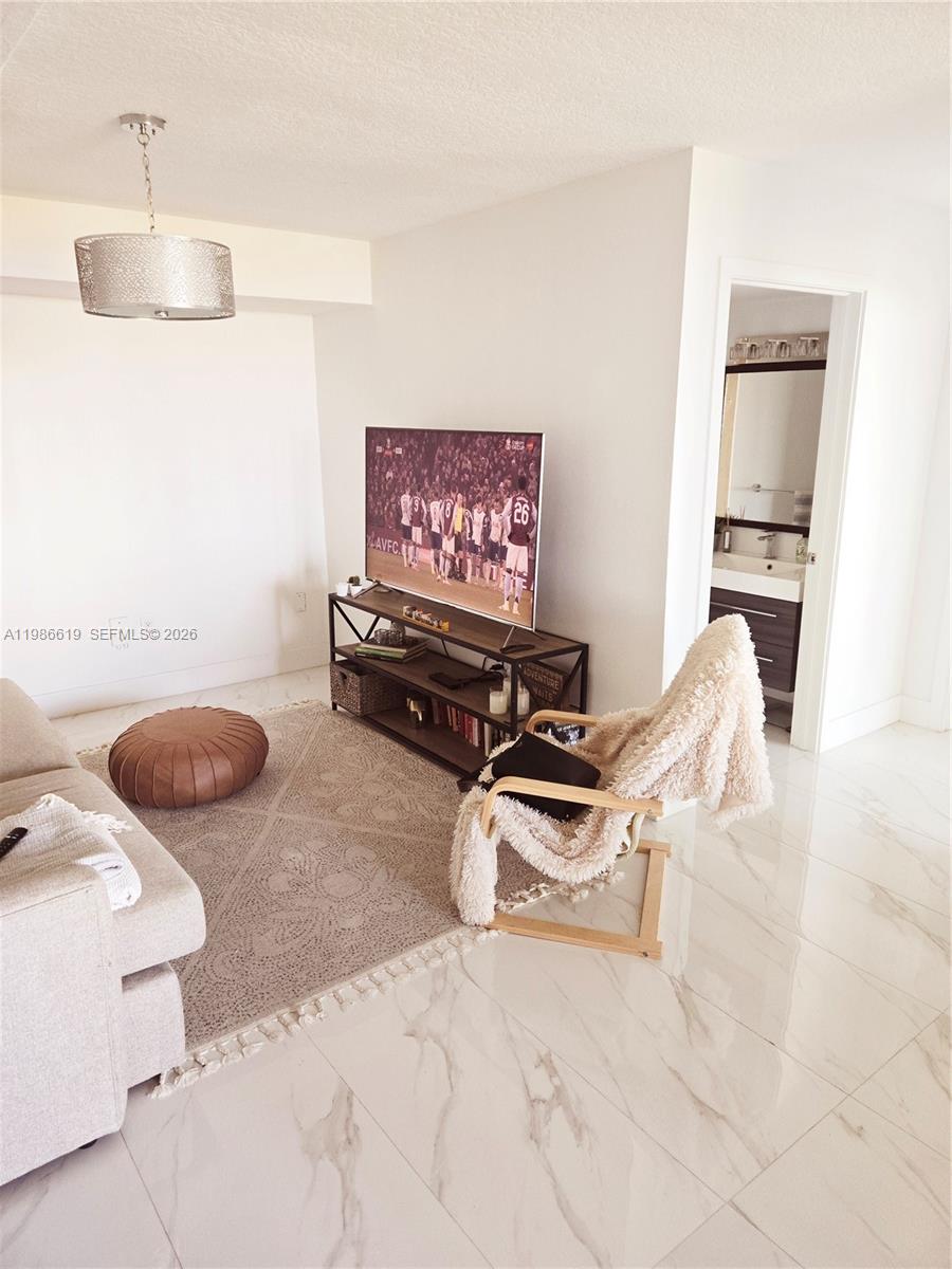 A living room features a television on a metal stand, a rug, and marble flooring — 1650 Coral Way # 702, Miami FL 33145, MIAMI, FL