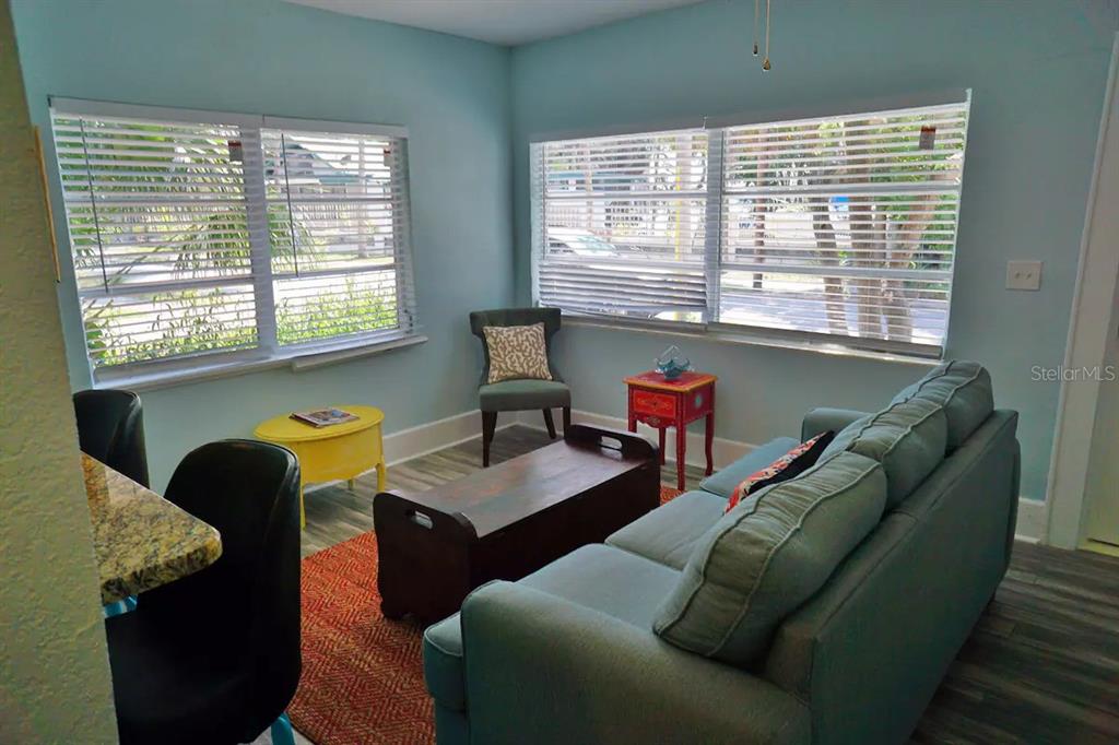 A living room features a teal sofa, a wooden coffee table, and large windows — 601 N OSCEOLA AVENUE, CLEARWATER, FL