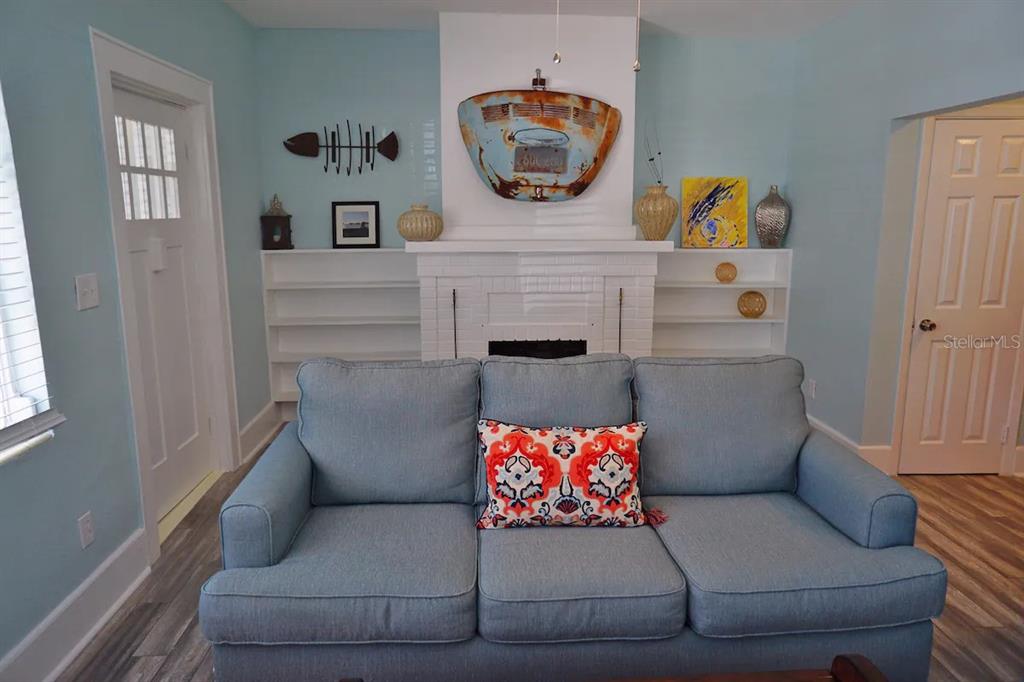 A living room features a blue sofa, a white fireplace, and built-in shelving units — 601 N OSCEOLA AVENUE, CLEARWATER, FL