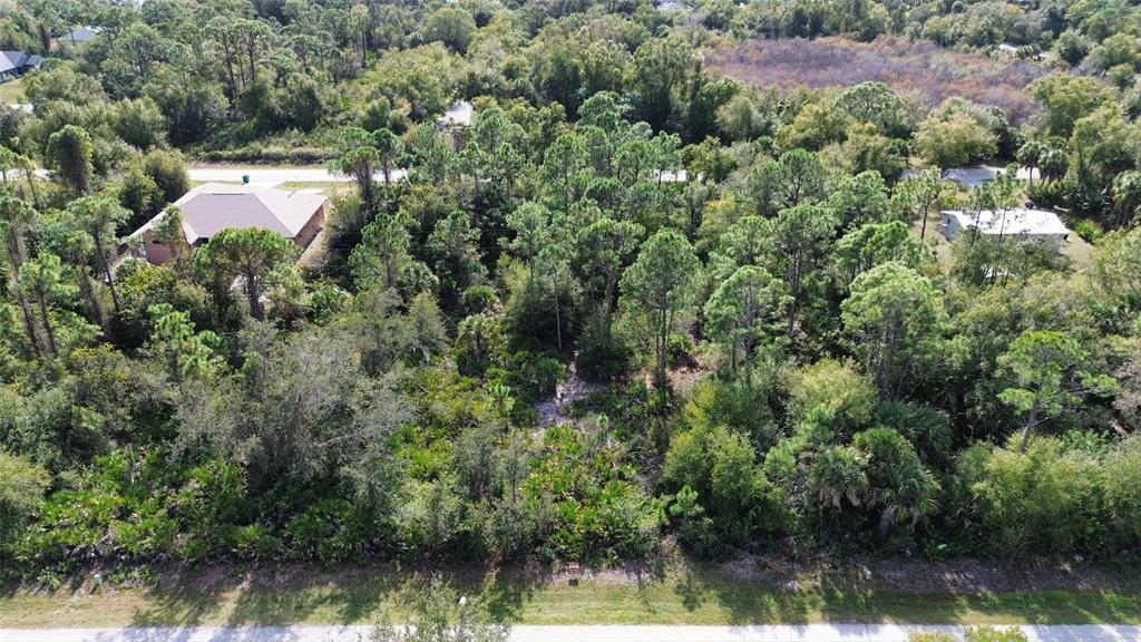 An aerial view shows a wooded, undeveloped lot situated between two residential houses — 23431 RACINE AVENUE, PUNTA GORDA, FL