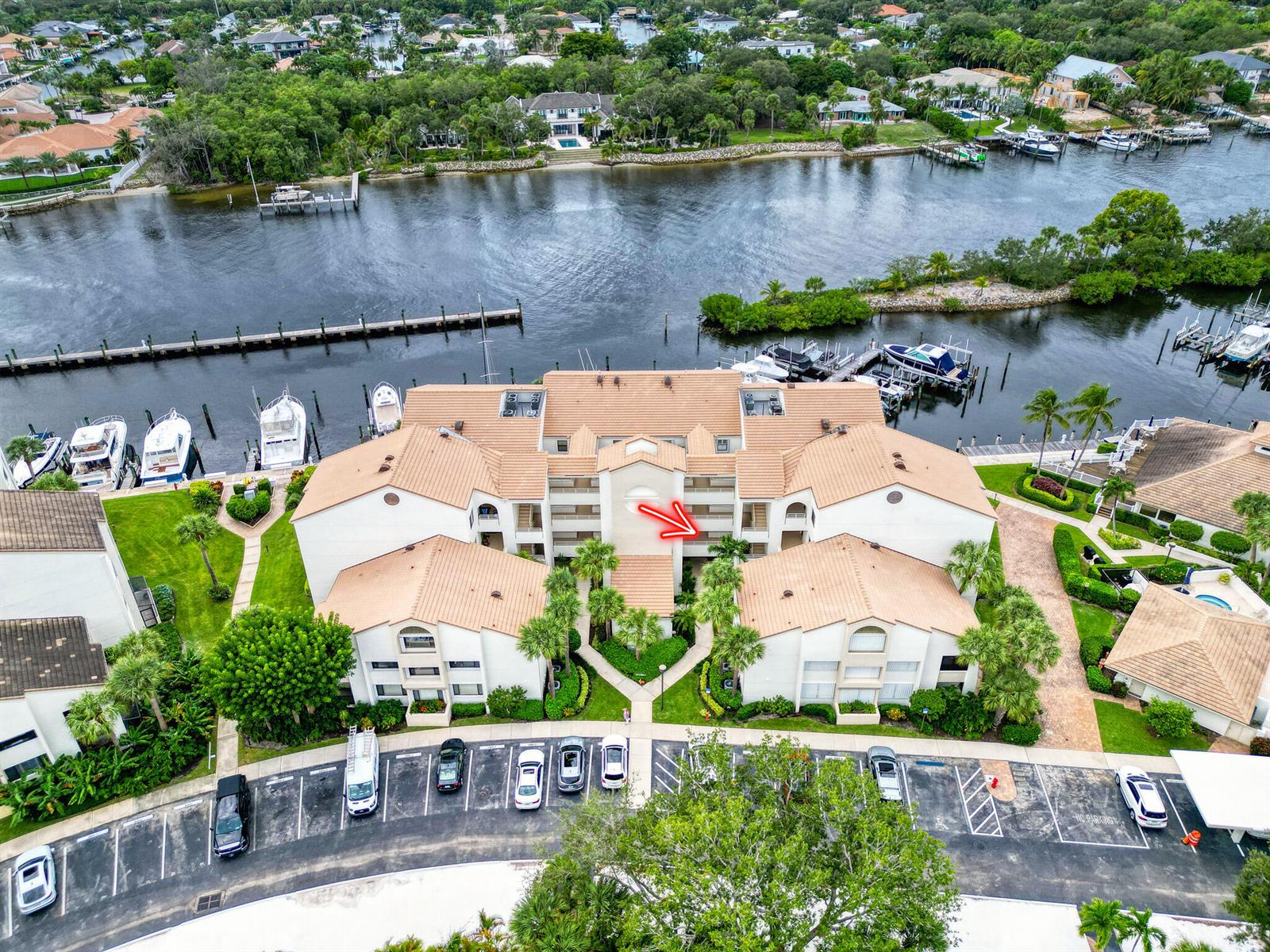An aerial view shows a multi-story residential building with a tile roof and parking lot — 827 Oak Harbour Drive, Juno Beach FL 33408, JUNO BEACH, FL
