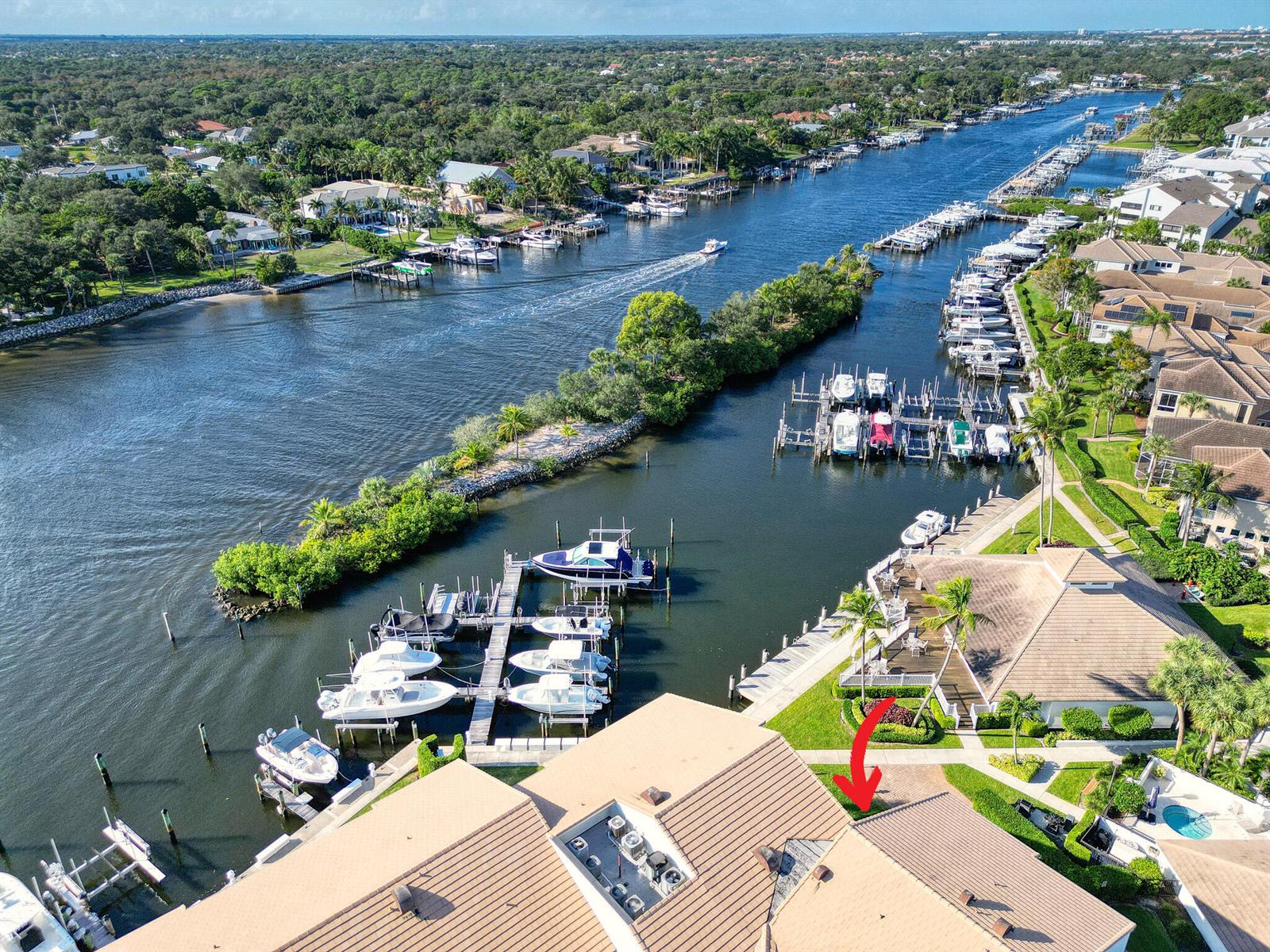 An aerial view shows a waterfront residential complex with boat slips and a canal — 827 Oak Harbour Drive, Juno Beach FL 33408, JUNO BEACH, FL