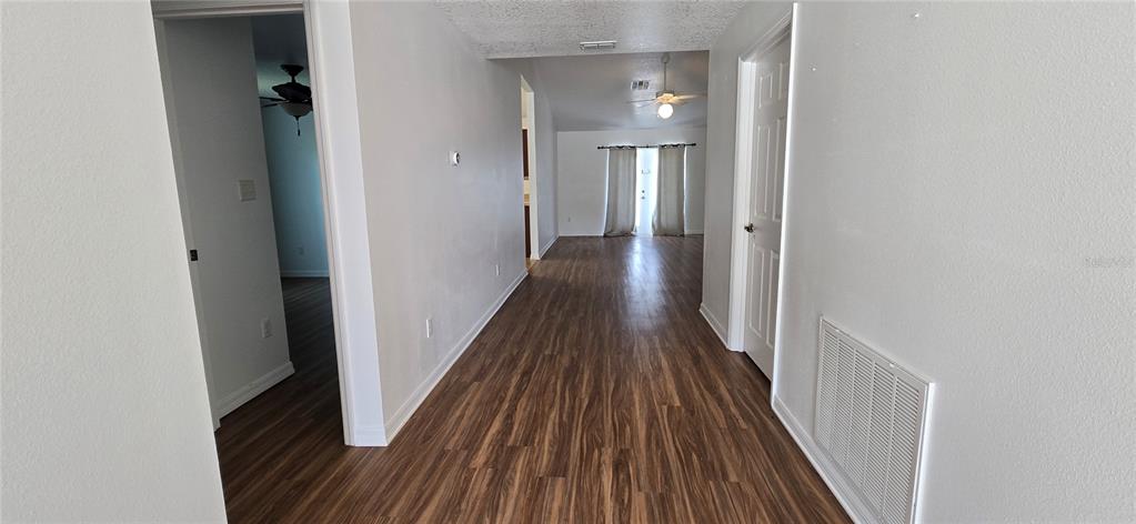 A hallway with wood-look flooring leads to a living area with sliding glass doors — 1500 KAYUNI DRIVE, MASCOTTE, FL