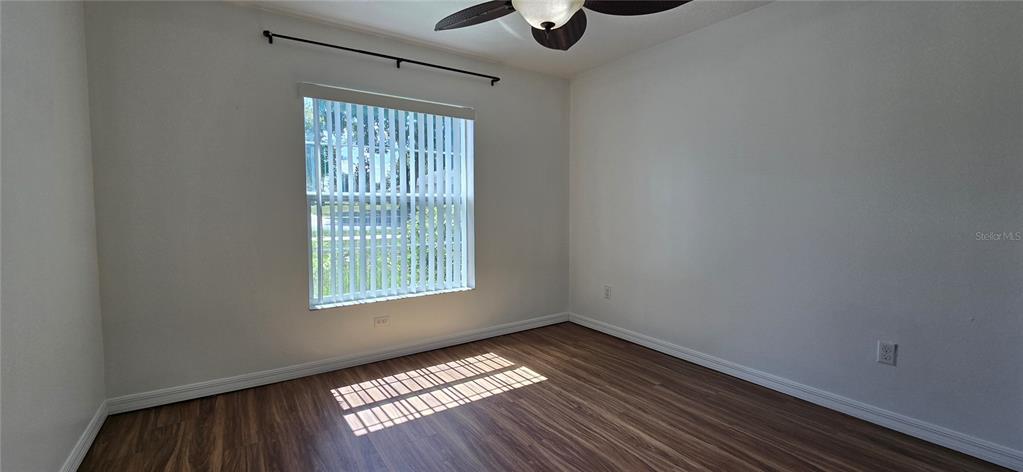 An empty bedroom features wood-look flooring, white walls, a ceiling fan, and a window — 1500 KAYUNI DRIVE, MASCOTTE, FL