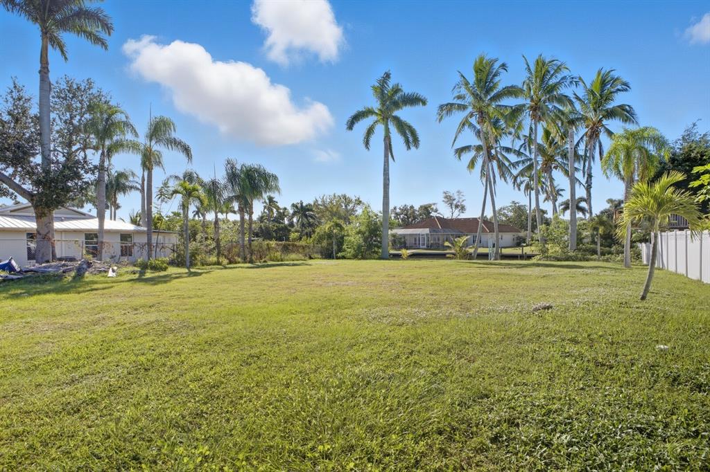 A large, grassy vacant lot features several palm trees under a clear blue sky — 6915 9TH AVENUE NW, BRADENTON, FL