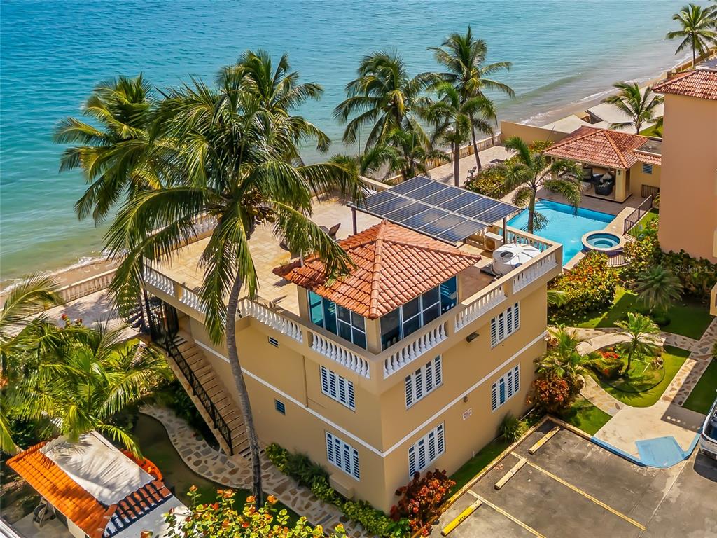 An elevated view of a beachfront building with a rooftop terrace, solar panels, and pool — 8 CONDO OCEAN VIEW CASTLE, AGUADA, PR