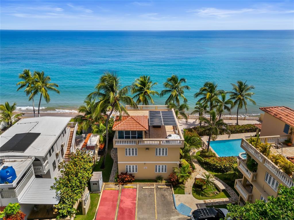 An aerial view shows a multi-story beachfront building with a pool and parking area — 8 CONDO OCEAN VIEW CASTLE, AGUADA, PR