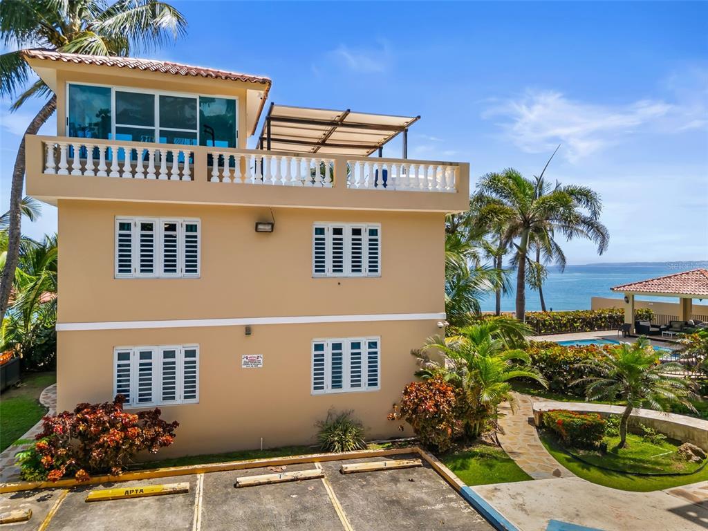 The exterior of a two-story tan building with a rooftop terrace and ocean views — 8 CONDO OCEAN VIEW CASTLE, AGUADA, PR