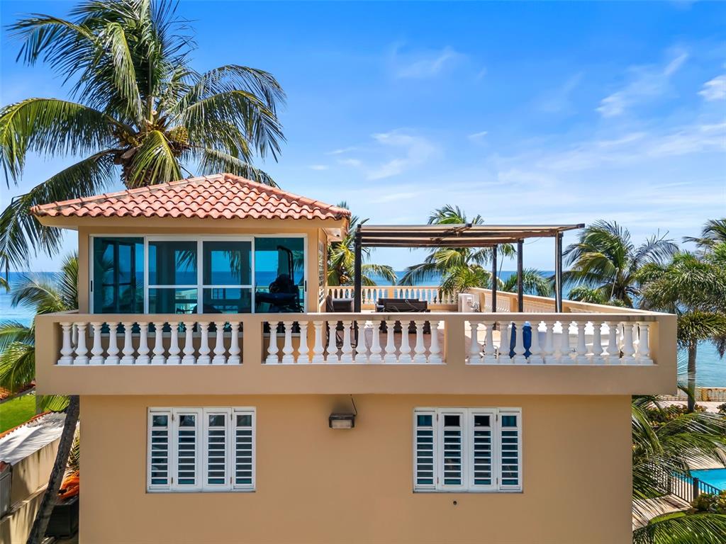 A two-story tan building features a second-floor balcony with a balustrade and a rooftop terrace — 8 CONDO OCEAN VIEW CASTLE, AGUADA, PR