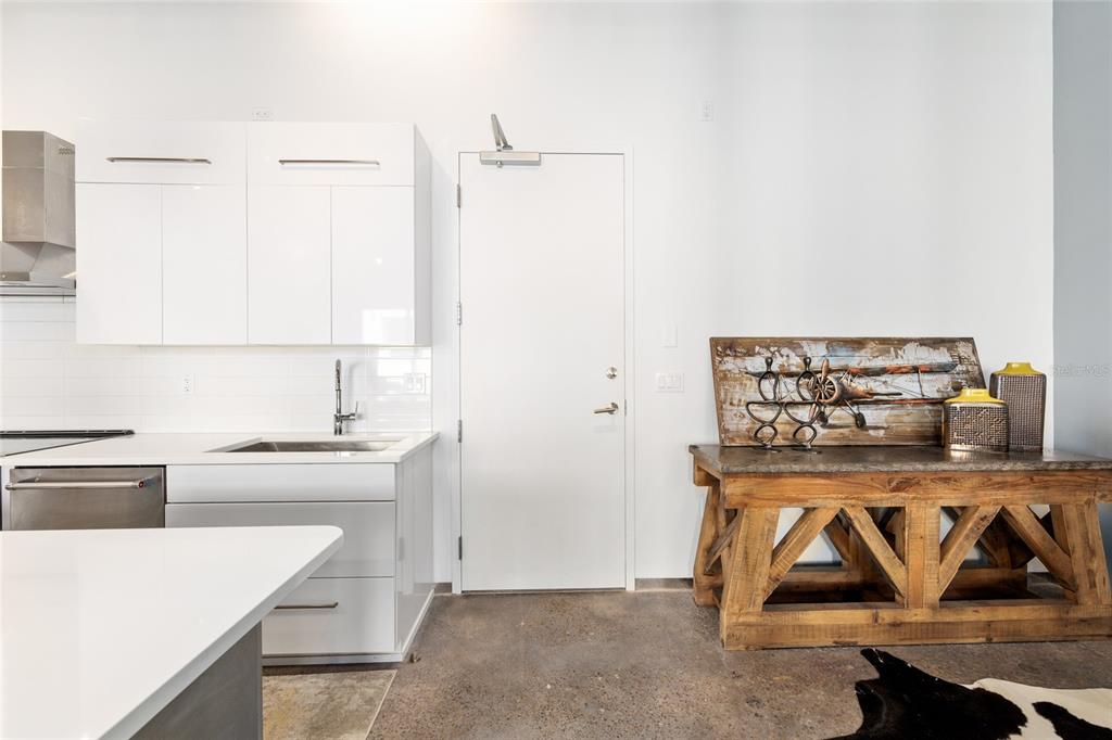 A modern kitchen features white cabinets, a stainless steel sink, and a rustic wooden console table — 302 SE BROADWAY STREET UNIT 330, OCALA, FL