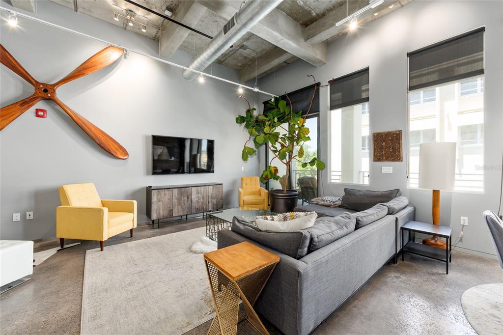 A modern living room features a large wooden propeller wall decoration and exposed concrete ceilings — 302 SE BROADWAY STREET UNIT 330, OCALA, FL