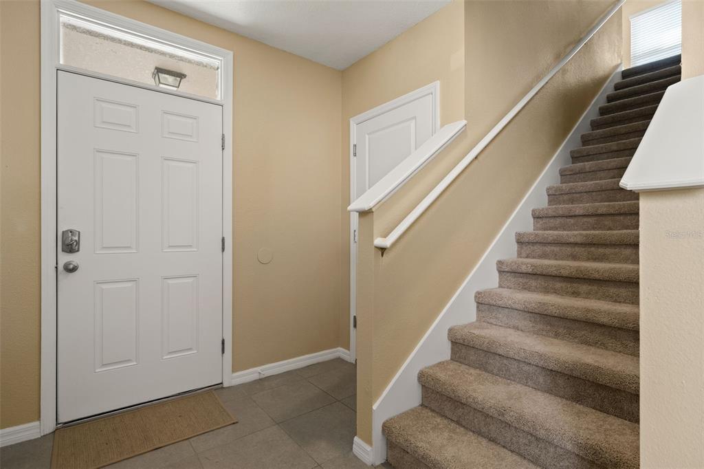 An entryway features a white front door, tiled flooring, and a carpeted staircase with railings — 6663 SEAWAY DRIVE, BROOKSVILLE, FL
