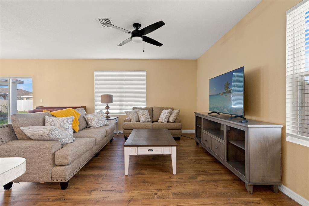 A living room features wood-look flooring, a beige sofa, a loveseat, and a television console — 6663 SEAWAY DRIVE, BROOKSVILLE, FL