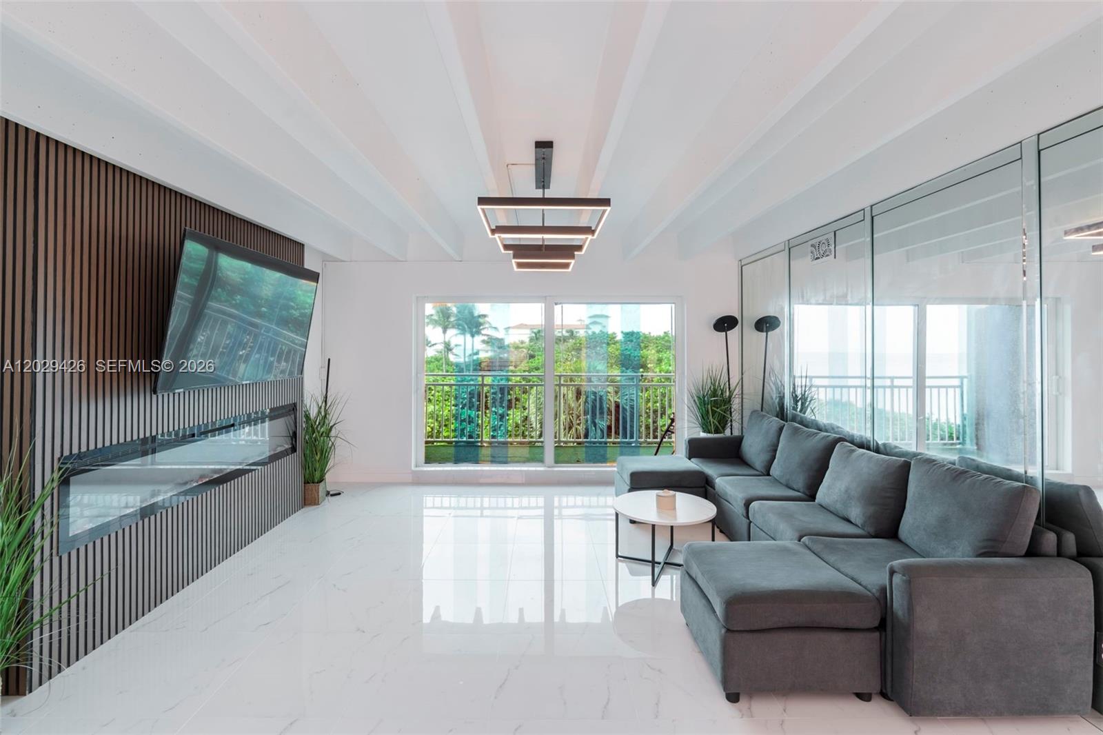 A modern living room features a slatted wood accent wall, fireplace, and gray sectional sofa — 4500 S Ocean Blvd # 405, Lantana FL 33480, LANTANA, FL