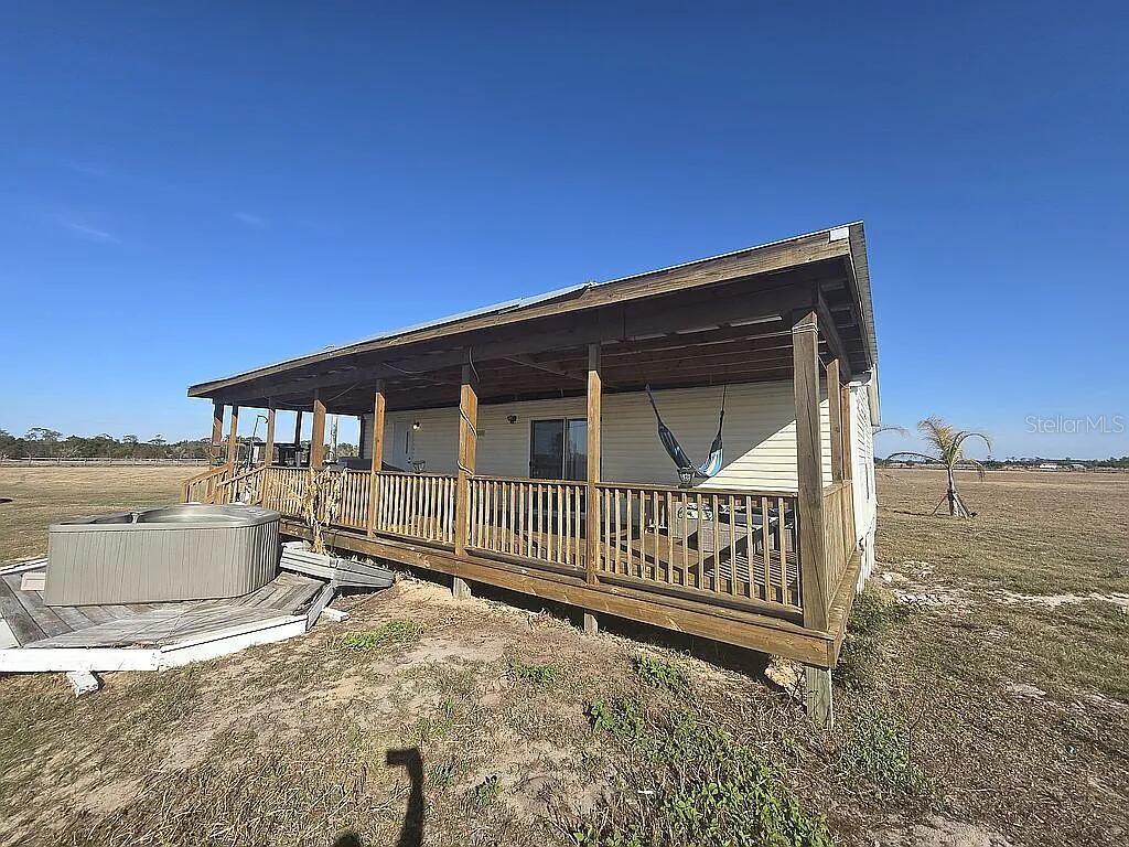 A mobile home with a large wooden porch and a hot tub in a field — 814 DACHSHUND ROAD, SEBRING, FL