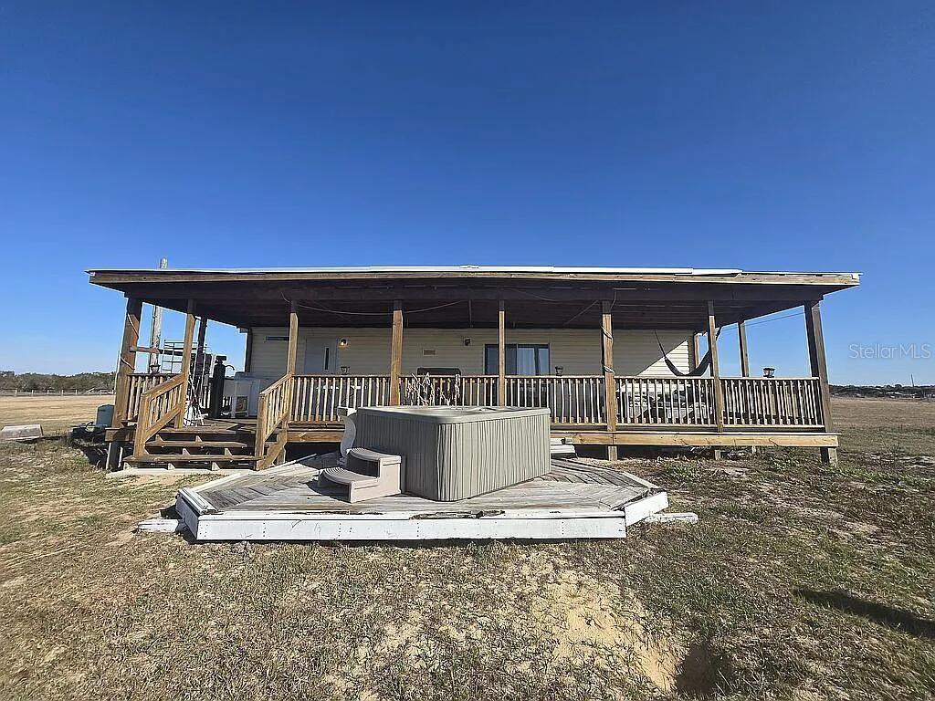 A mobile home features a large covered wooden deck with a hot tub in front — 814 DACHSHUND ROAD, SEBRING, FL