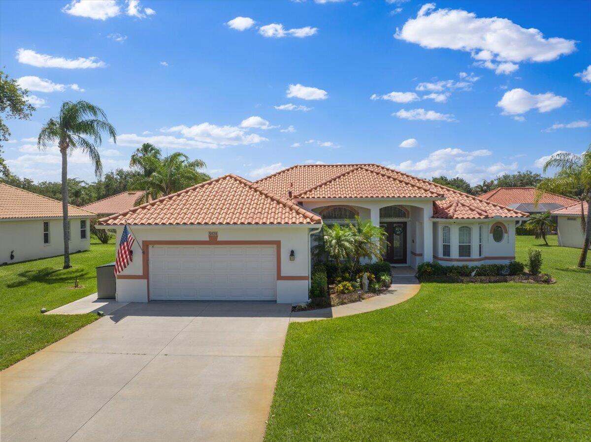 A single-story house with a tile roof, two-car garage, and a front lawn — 5828 Pine Ridge Circle, Vero Beach FL 32967, VERO BEACH, FL