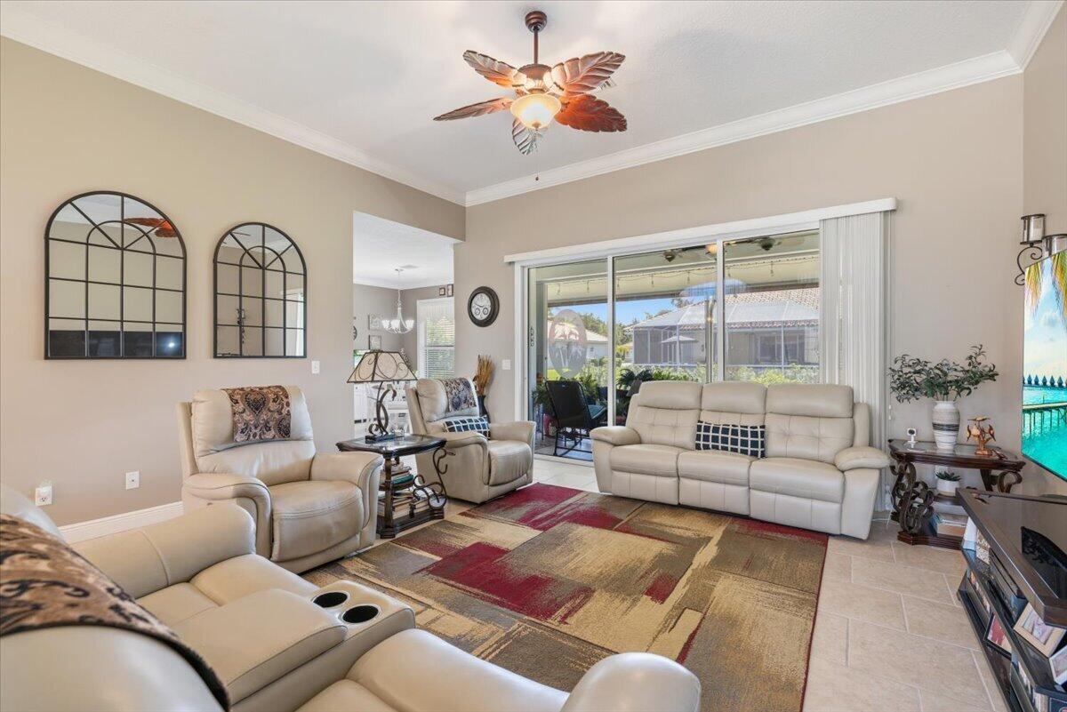 A living room features light-colored leather furniture, a patterned area rug, and a ceiling fan — 5828 Pine Ridge Circle, Vero Beach FL 32967, VERO BEACH, FL