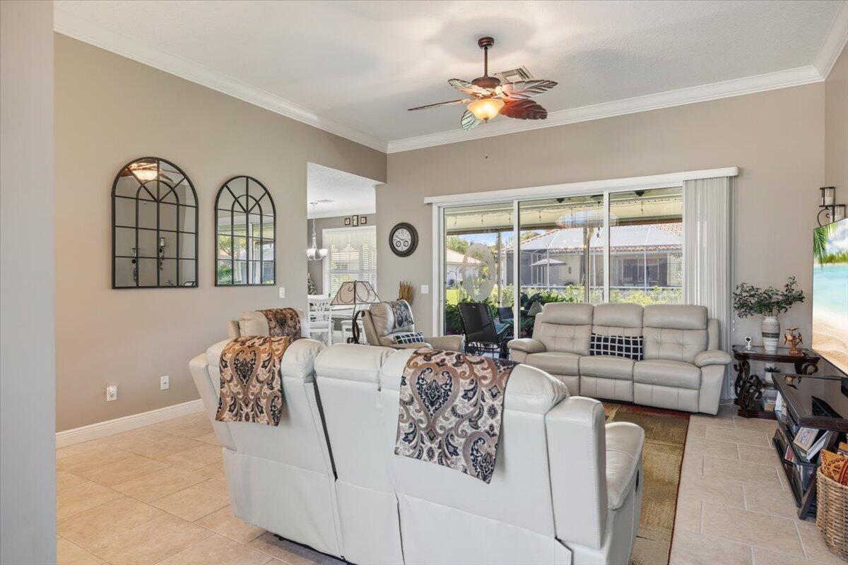 A living room features light-colored tile floors, a ceiling fan, and large sliding glass doors — 5828 Pine Ridge Circle, Vero Beach FL 32967, VERO BEACH, FL