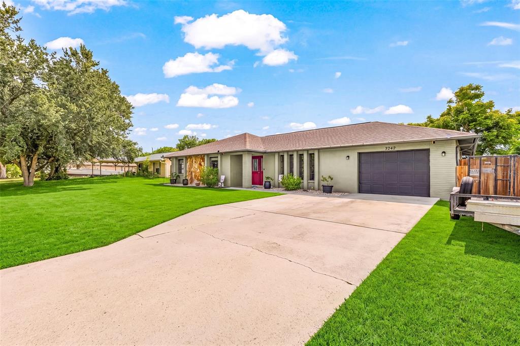 A single-story house with a light green brick exterior, a dark garage, and a driveway — 3242 CARDIFF ST, PUNTA GORDA, FL