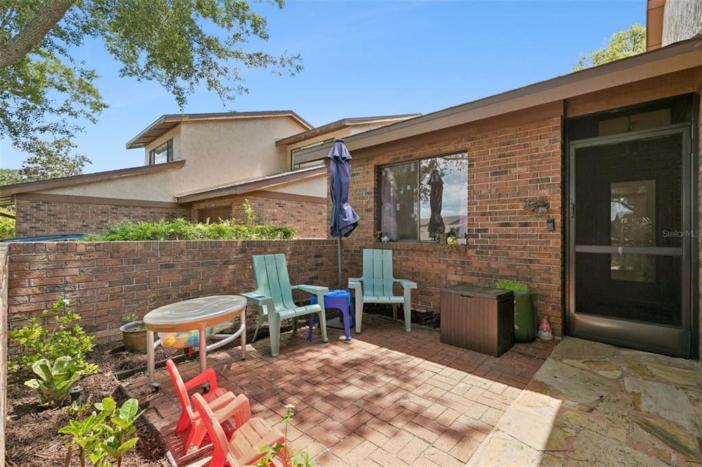 A brick patio features two light blue chairs, a small table, and a screen door — 335 GOLFSIDE COVE, LONGWOOD, FL