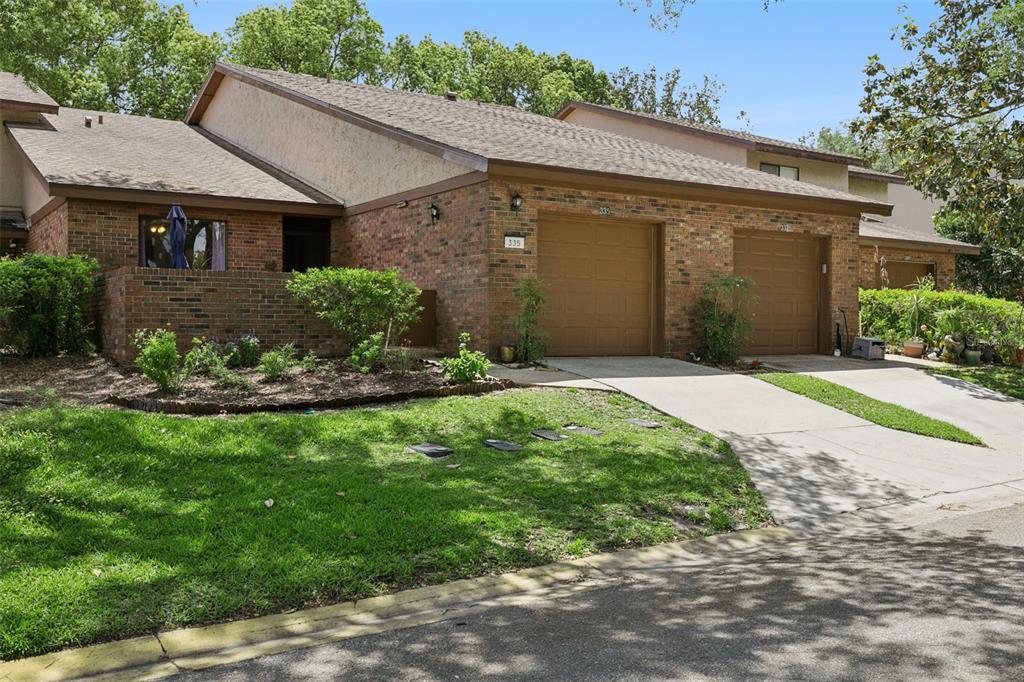 A brick-walled entryway features a glass-paneled front door, a transom window, and a cat-themed doormat — 335 GOLFSIDE COVE, LONGWOOD, FL