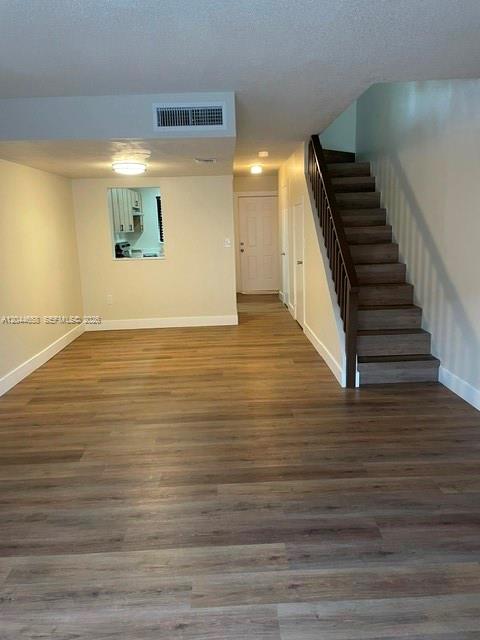 An interior view shows a room with wood-look flooring, a staircase, and a kitchen pass-through window — 8020 SW 152nd Ave # 306, Miami FL 33193, MIAMI, FL