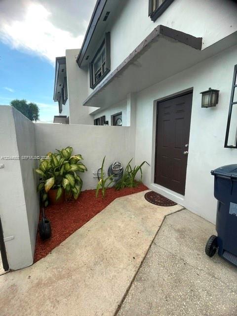 A concrete walkway leads to a dark brown front door beside a small garden bed — 8020 SW 152nd Ave # 306, Miami FL 33193, MIAMI, FL