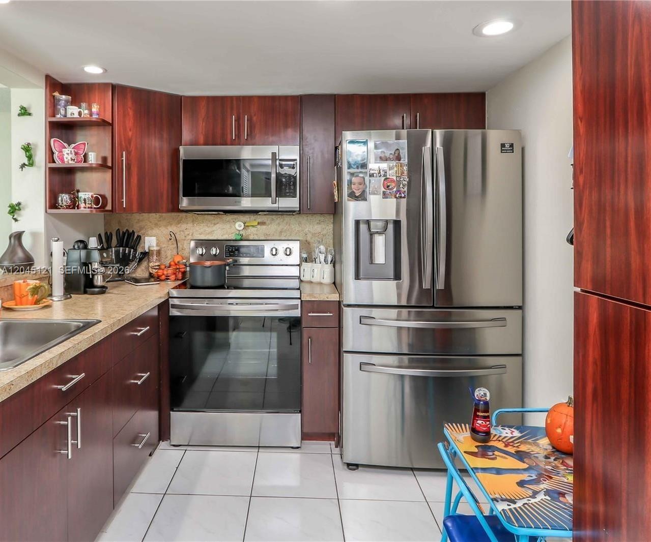 A kitchen with dark wood cabinets, stainless steel appliances, and light-colored tile flooring — 2055 SW 122nd Ave # 306, Miami FL 33175, MIAMI, FL