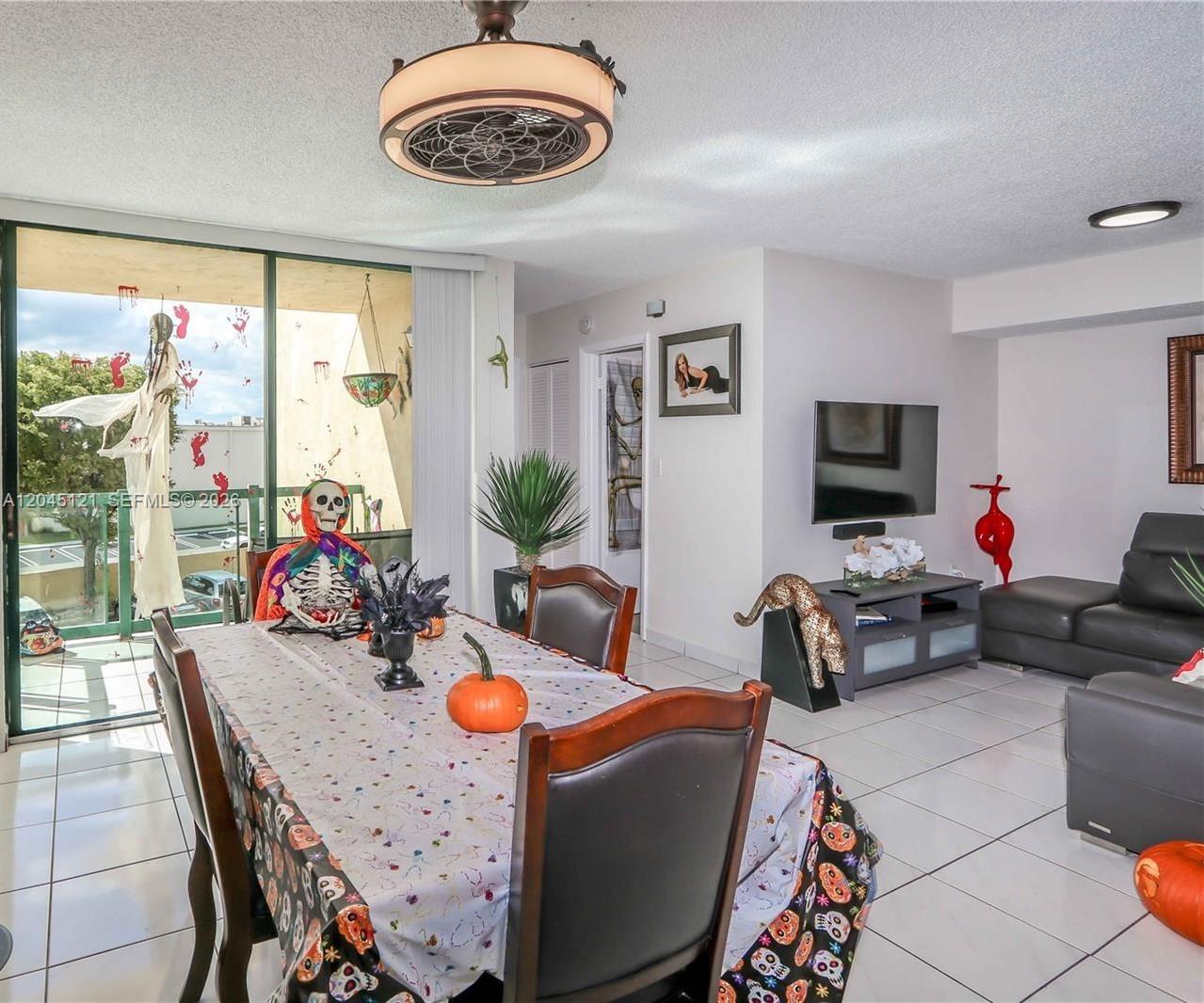 A dining area and living room feature tile floors, a ceiling fan, and Halloween decorations — 2055 SW 122nd Ave # 306, Miami FL 33175, MIAMI, FL