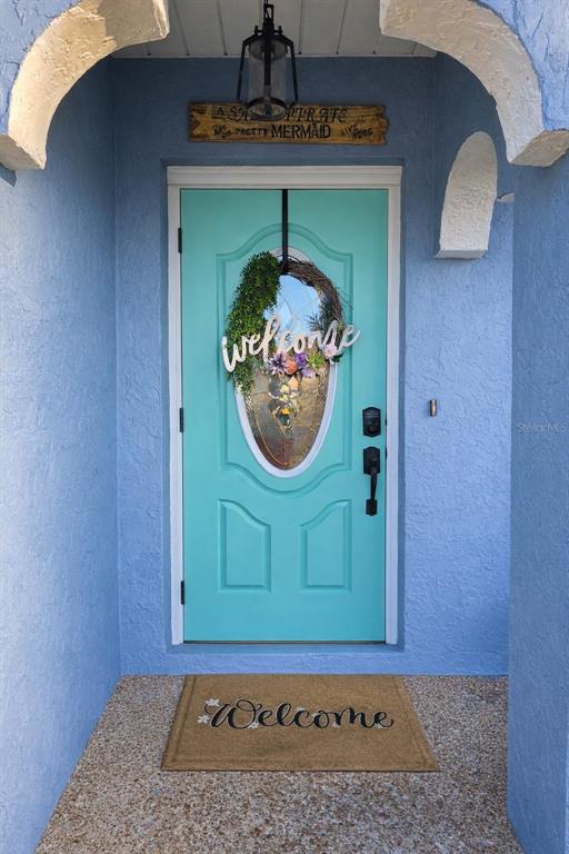 A bright blue front door with a welcome wreath sits under an arched entryway — 441 CORONADO ROAD, VENICE, FL