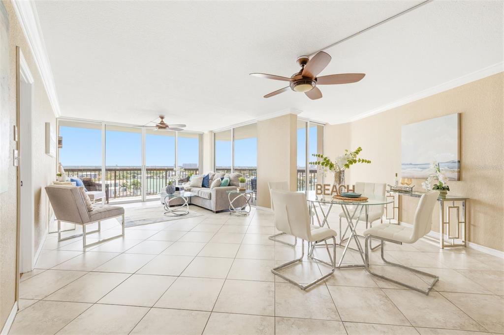 An open-concept living and dining area features tile floors, a ceiling fan, and balcony views — 9415 BLIND PASS ROAD UNIT 806, ST PETE BEACH, FL