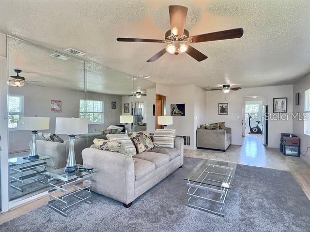 A living room features a beige sofa, glass coffee tables, and a mirrored wall — 5227 81ST LANE N UNIT 26, ST PETERSBURG, FL