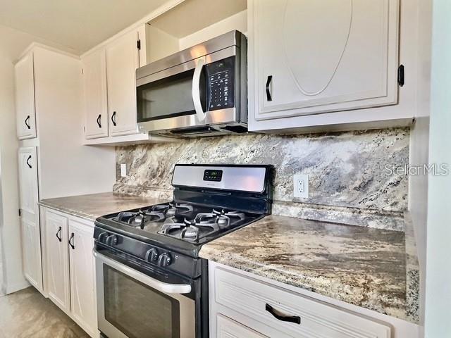 A kitchen features white cabinets, granite countertops, and a stainless steel stove and microwave — 5227 81ST LANE N UNIT 26, ST PETERSBURG, FL