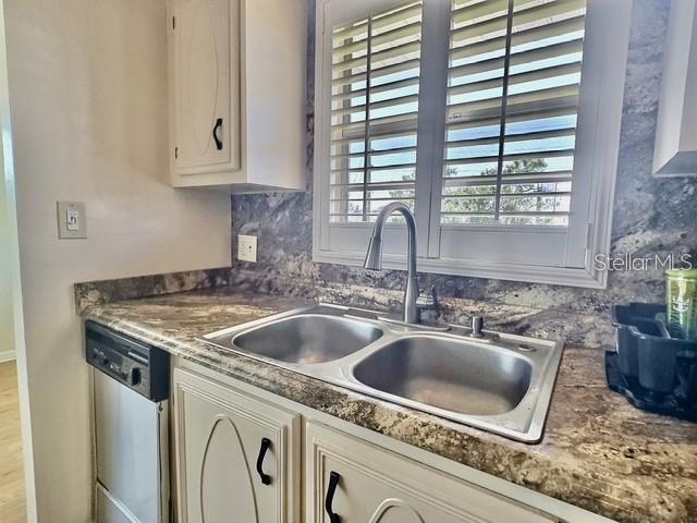 A kitchen sink with a gooseneck faucet sits in a granite countertop with white cabinets — 5227 81ST LANE N UNIT 26, ST PETERSBURG, FL
