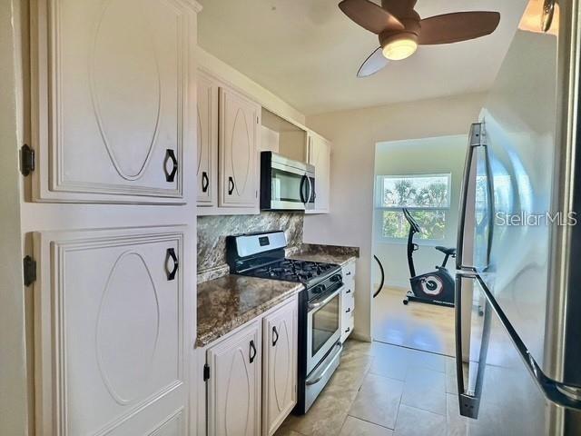 A kitchen with white cabinets, a stainless steel stove, and a view into a workout room — 5227 81ST LANE N UNIT 26, ST PETERSBURG, FL