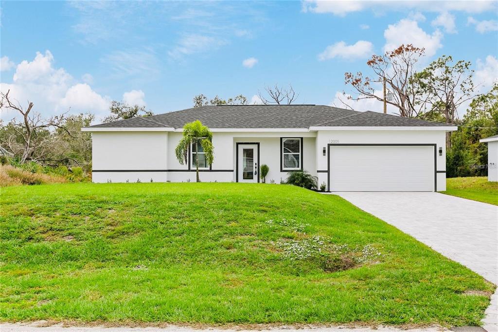 A single-story white house with a dark roof, a two-car garage, and a grassy lawn — 189 STATLER STREET, PORT CHARLOTTE, FL