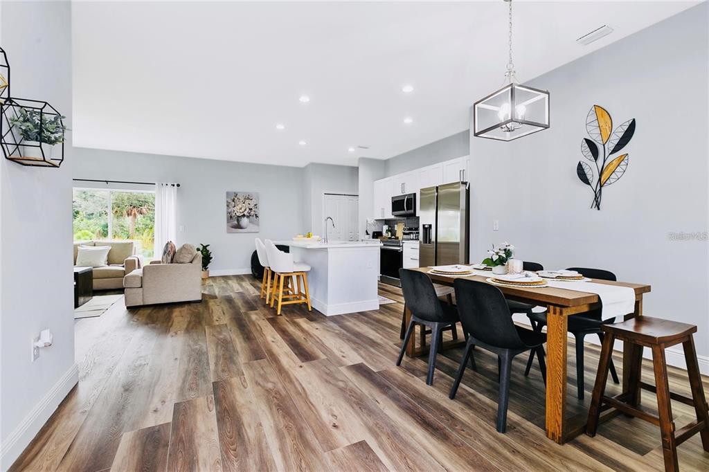 An open-concept kitchen and dining area features wood-look flooring, white cabinetry, and a kitchen island — 189 STATLER STREET, PORT CHARLOTTE, FL