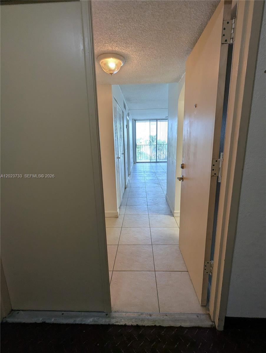 A view through an open doorway shows a tiled hallway leading to a balcony — 16751 NE 9th Ave # 408, North Miami Beach FL 33162, NORTH MIAMI BEACH, FL