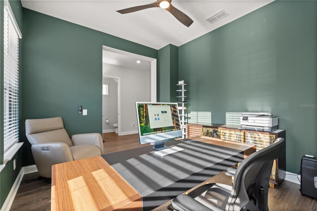 A home office features dark green walls, a wood desk, a computer, and a recliner — 543 WISHBONE LANE, LAKE MARY, FL