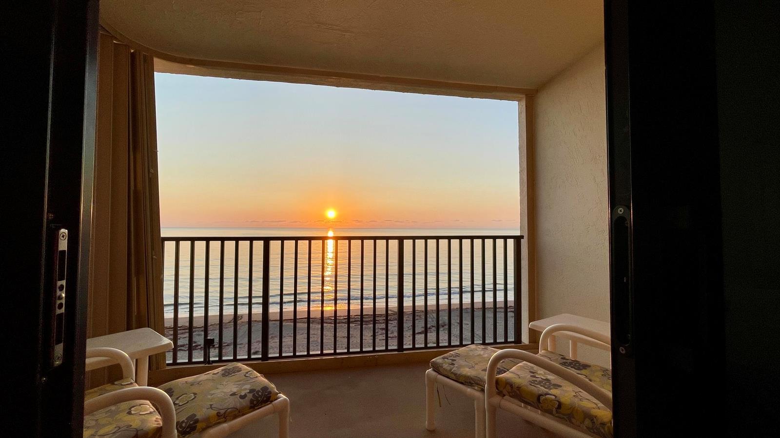 A balcony with two chairs overlooks the ocean during a sunset — 10044 S Ocean Drive # 805, Jensen Beach FL 34957, JENSEN BEACH, FL