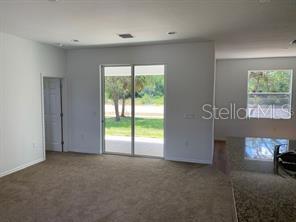 A carpeted living room features a sliding glass door leading to a backyard patio — 3035 BREWSTER ROAD, NORTH PORT, FL