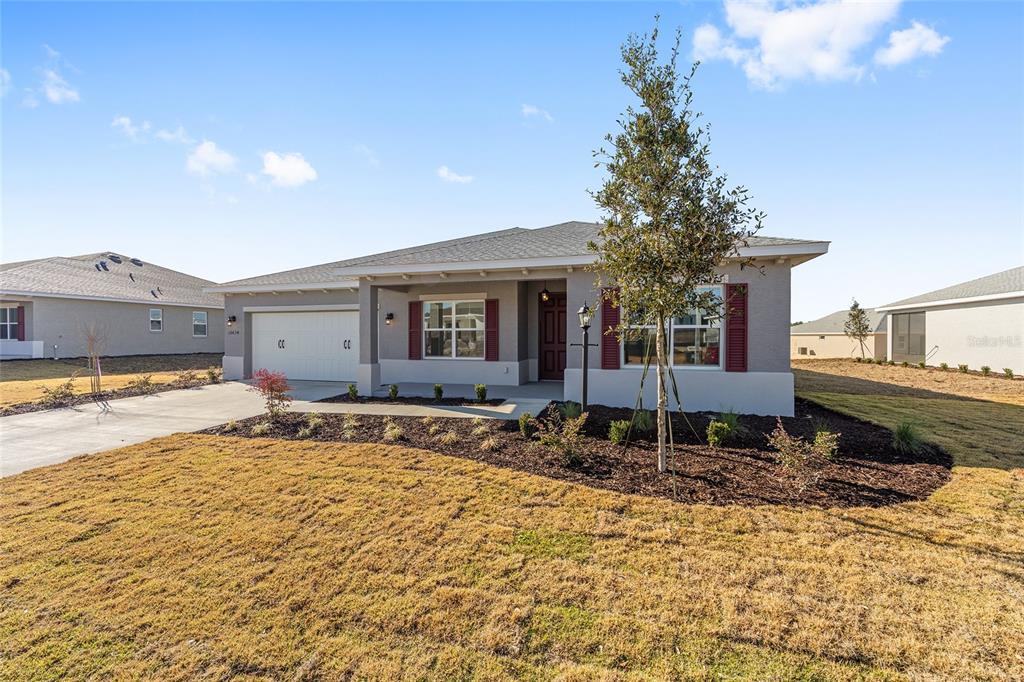 A single-story suburban house with a gray exterior, red shutters, and a two-car garage — 10634 SW 101ST LANE ROAD, OCALA, FL