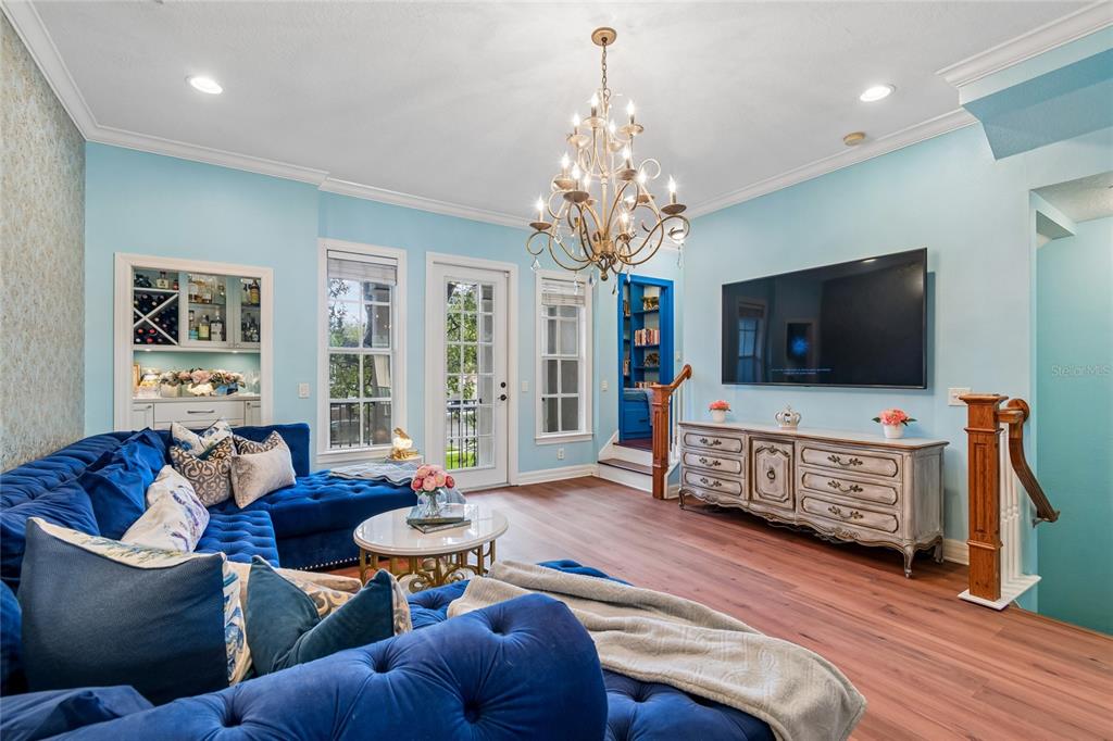 A living room features a blue velvet sectional, a chandelier, and a wall-mounted television — 111 S DELAWARE AVENUE UNIT 3, TAMPA, FL