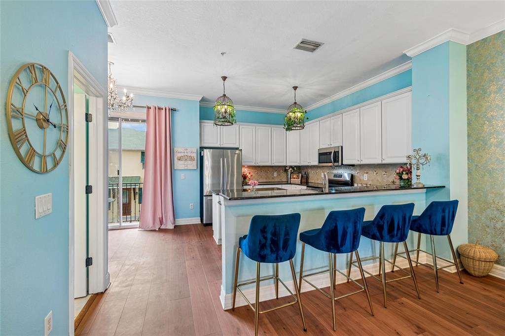 A kitchen features white cabinets, a black countertop, blue bar stools, and light blue walls — 111 S DELAWARE AVENUE UNIT 3, TAMPA, FL