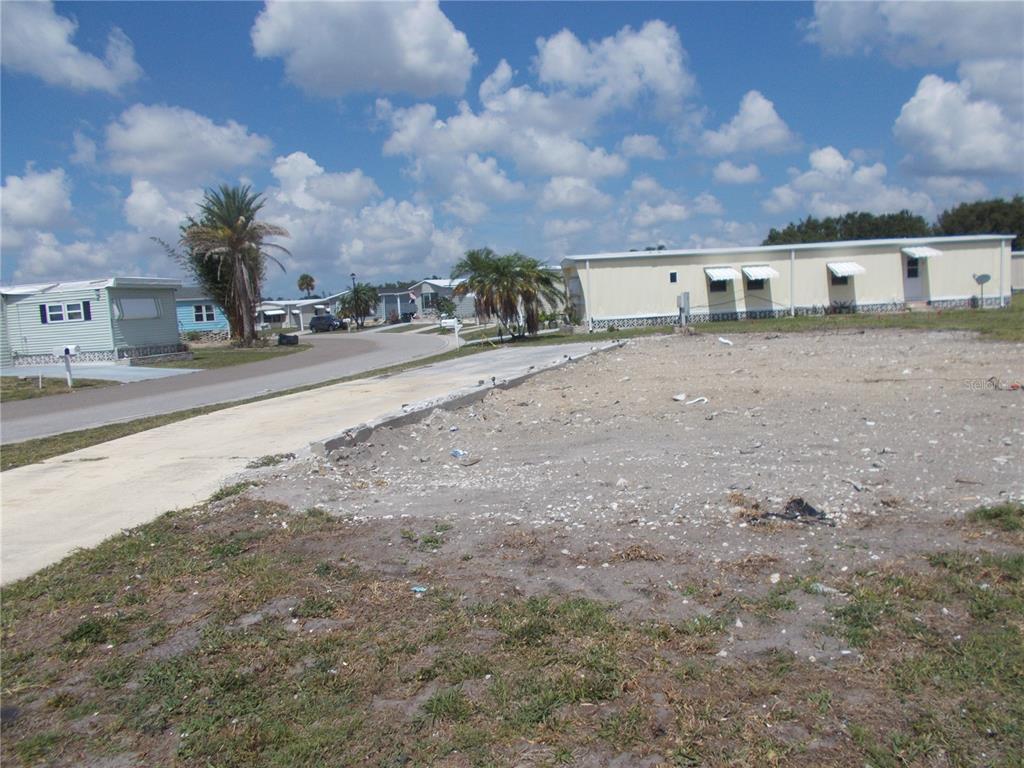 A vacant lot with a concrete driveway in a mobile home community under a cloudy sky — 6581 CENTER LANE, NORTH PORT, FL
