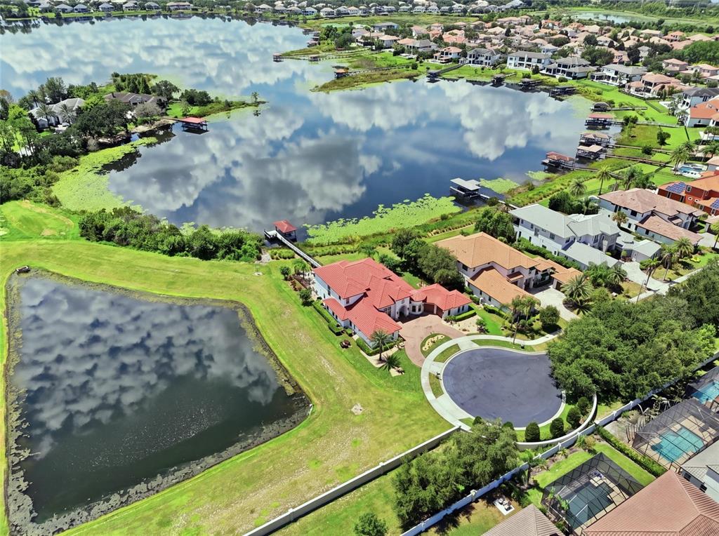 A backyard pool and spa overlook a lake with a dock and evening fireworks display — 12102 MONTALCINO CIRCLE, WINDERMERE, FL