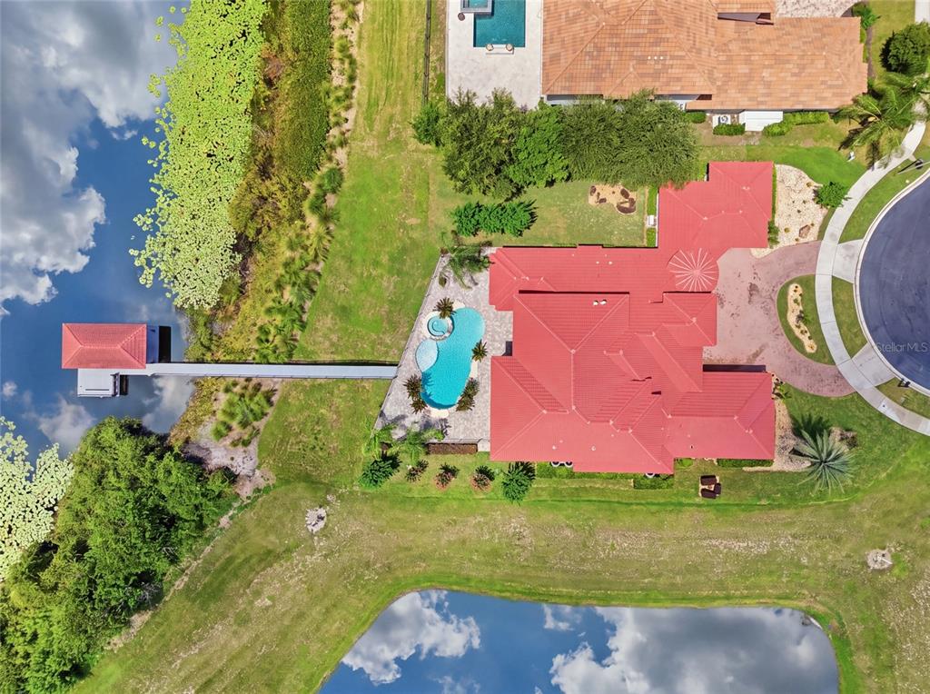An aerial view shows a large house with a red roof situated between two lakes — 12102 MONTALCINO CIRCLE, WINDERMERE, FL