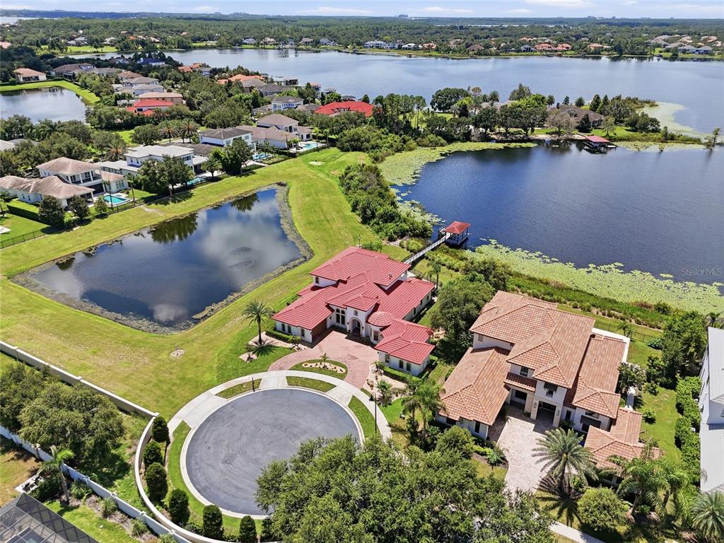 An aerial view shows two large houses with red tile roofs near a lake — 12102 MONTALCINO CIRCLE, WINDERMERE, FL