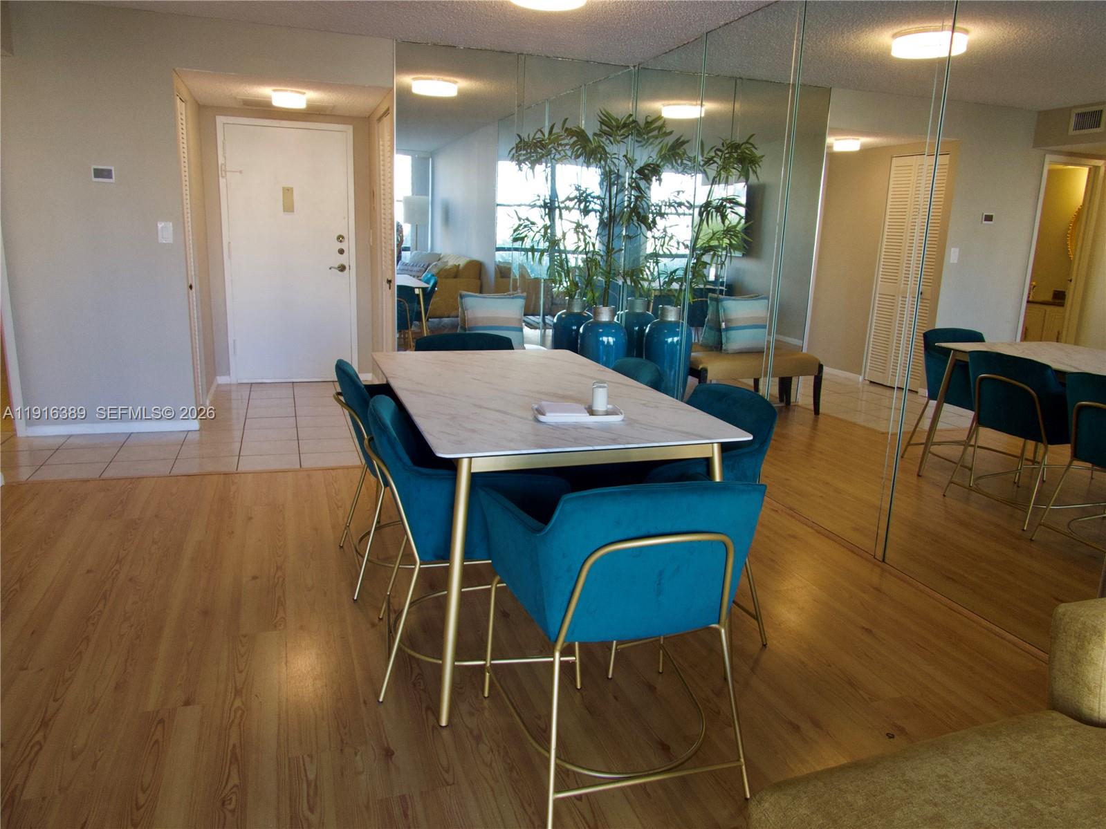 A dining area features a marble-topped table with blue velvet chairs and mirrored walls — 800 Parkview Dr # 402, Hallandale Beach FL 33009, HALLANDALE BEACH, FL